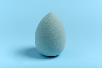 Blue cosmetic makeup sponge on a minimal background. Egg shape. Tool for applying foundation cream