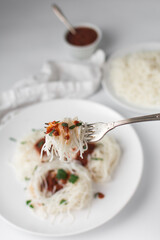 Rice noodles with tomato sauce and basil on a silver fork, eating rice noodles with a fork, Rice vermicelli 