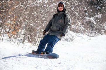 Fototapeta na wymiar a man on a snowboard rides down the side of the mountain
