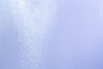 Obraz premium Close-up of uneven backlit glass surface with abstract lines and patterns. Light blue hue, copy space. High resolution full frame abstract background.
