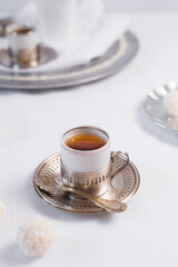 Dos tazas de té clásico con dulces chocolates blancos cubiertos de coco en el cuadro blanco	