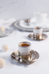 Dos tazas de té clásico con dulces chocolates blancos cubiertos de coco en el cuadro blanco	