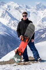 Portrait of a man with snowboard on top of a snowy mountain