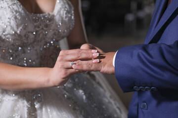 Wedding bride putting wedding ring on groom's finger