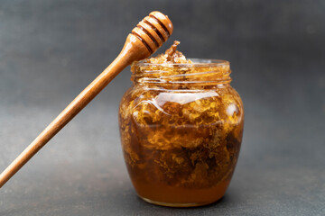Golden honeycomb and beeswax in a jar of honey on the table. Sweet organic honey in a jar with a...