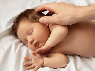 Small baby girl sleeping. Newborn baby in a wrap on white blanket. Beautiful portrait of little child girl 7 days, one week old. Baby lying on back on white background. Motherhood