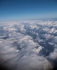 Aerial view of snow covered rocky mountains in Canada or Canadian Rockies as seen from window seat of airplane while in flight travelling on plane from Alberta, Canada to British Columbia 