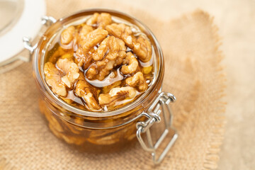 Walnuts in honey close-up. Jar of honey and nuts on a wooden background. Sweet and healthy eating dessert rich in nutrient