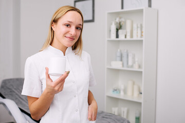Portrait of female professional beauty doctor holding product in a hand.
