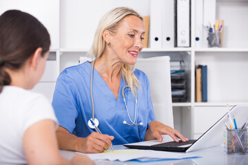 Portrait of mature female doctor listening to patient complaints at clinic