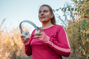 Active sport caucasian  woman in white wireless headphones running along outdoor in forest park in nature
