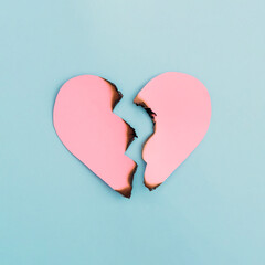 Broken heart symbol made with burnt pink paper on pastel blue background. Minimal art creative...