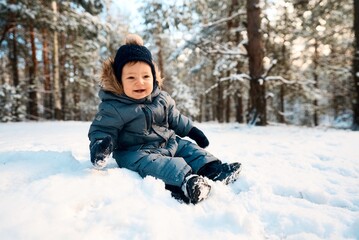Fototapeta na wymiar A little boy in the snow. Happy child walking through winter forest