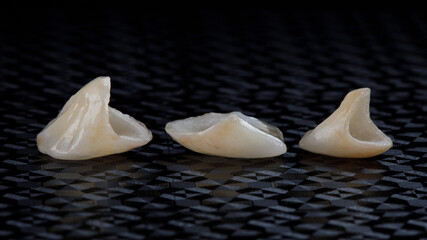 Three beautiful dental crowns from ceramics on a textured black background