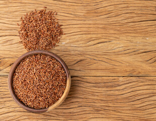 Raw red rice in a bowl over wooden table with copy space