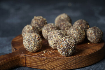 Healthy homemade energy balls on wooden plate. Vegan candies, sweets made of nuts and dates.
