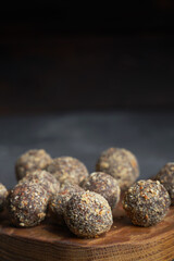 Healthy homemade energy balls on wooden plate. Vegan candies, sweets made of nuts and dates.