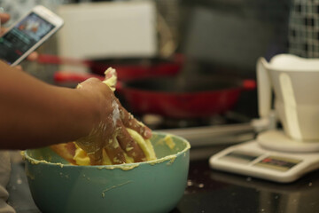 preparing a recipe from the internet in a bowl with bear hands with blurred effect in the background and phone and skillets