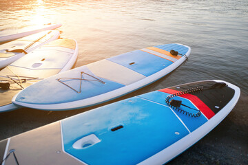 SUP Stand up paddle board on the background blue water. - obrazy, fototapety, plakaty
