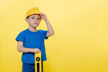 Little boy in yellow helmet builder with level tool