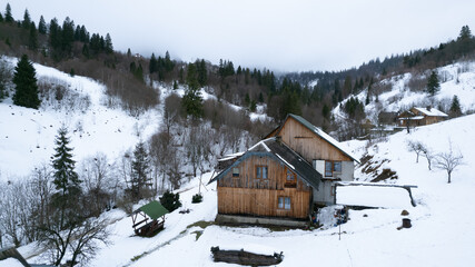 Winter vacation holiday wooden house in the mountains covered with snow and blue sky. Clouds over the mountains