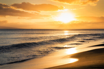 Warm calm waves greet this beautiful beach at sunset in Maui Hawaii