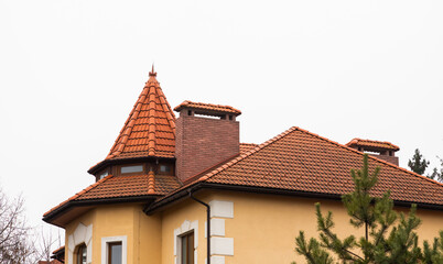 The roof of the house is made of red metal tiles, a beautiful large chimney