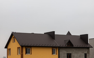 The roof of the house is made of red metal tiles, a beautiful large chimney