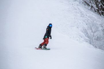 a girl on a snowboard rides down the side of the mountain