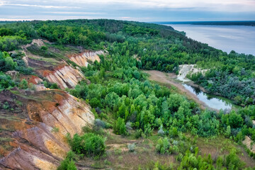 Colorful clay hills overgrown with green trees. Natural abstract landscape, aerial view from drone