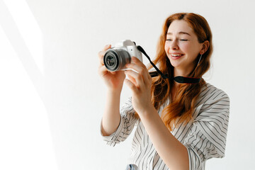 Laughing young woman taking photos with a modern camera, laughing, enjoying the moment