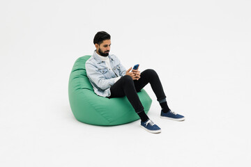 Young man sitting comfy soft violet armchair holding telephone chatting colleagues on white background