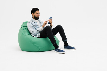Young man sitting comfy soft violet armchair holding telephone chatting colleagues on white...