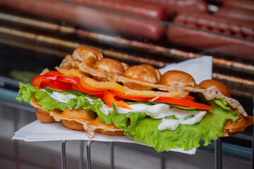Fresh waffle sandwich with pepper, lettuce, cheese on counter at summer local food market - close up view. Outdoor cooking, gastronomy, street food and vegetarian concept
