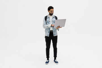 Indian handsome young man with backpack standing and using laptop