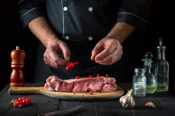 Cook prepares raw veal meat. Before baking, the cook puts the viburnum on the beef. National dish is being prepared in the restaurant kitchen