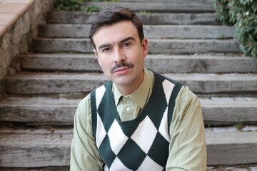 Man with a mustache wearing sleeveless rhombus sweater