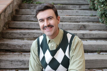Man with a mustache wearing sleeveless rhombus sweater
