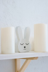 On the shelf there are two candles and a bunny (decor)