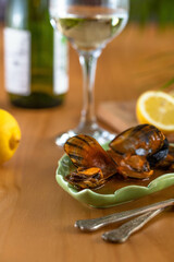 Steamed mussels on a wooden table with lemons and a glass of wine.