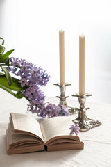 open book and two candles on a table with spring flowers