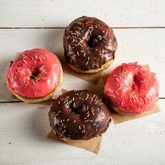 Donuts with icing on a white wooden background.