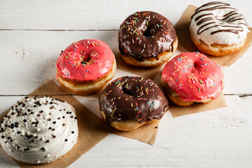 Donuts with icing on a white wooden background.