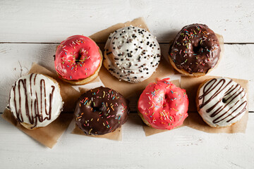 Fototapeta na wymiar Delicious donuts with icing on a white wooden background.