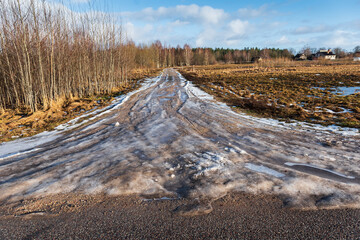 Melting ice on a country road in winter day