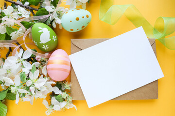 postcard mockup. Easter greeting card. colorful Easter eggs, flowering branches, willow twigs and an envelope with a white blank for the text.