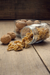 Nuts coming out of a glass jar on a wooden table in a dark environment.. High quality photo