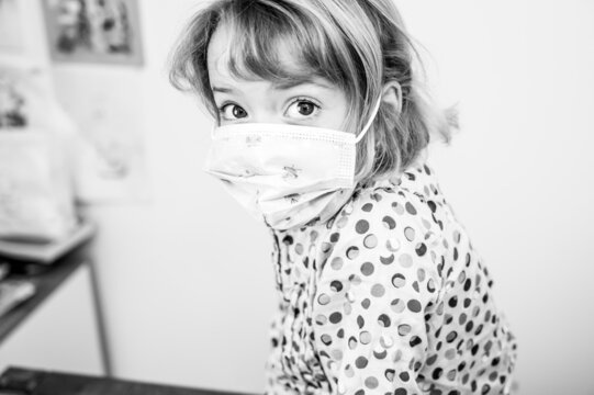 Portrait of cute blonde girl with medical face mask at home.