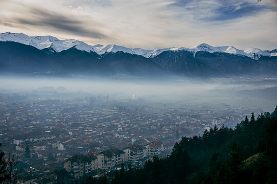 Pirin mountain, Bulgaria. Covered in snow peak in winter skiing season. Mist fog and Razgrad city below the mountain
