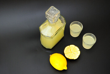 Limoncello is a large Italian alcohol and pieces of ripe citus on a black background.